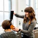 Coiffeuse effectuant une coiffure dans son salon