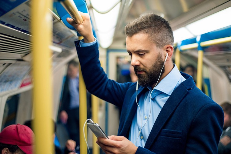 reprendre une boutique loin de son domicile - un homme qui tient la barre de metro et regarde son portable