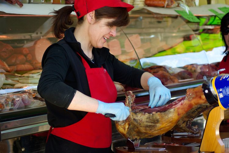 Bouchère coupant la viande dans une boucherie